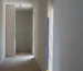 Minimalist hallway with light, smooth mineral lime walls and a natural wood floor, the kind of finish interior designers specify with Marmorino plaster in Miami